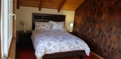 ein Schlafzimmer mit einem großen Bett und einer Holzwand in der Unterkunft Rancho Eben Ezer in Puyehue
