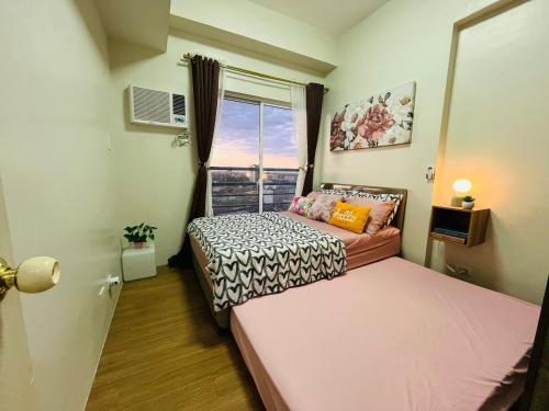 een kleine slaapkamer met een bed en een raam bij The Elevated Abode - ComfyCosy 1-br at The Loop in Cagayan de Oro