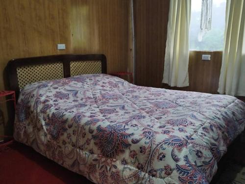 uma cama num quarto com um cobertor em Cabaña Rural de Montaña en La Cima de Dota 