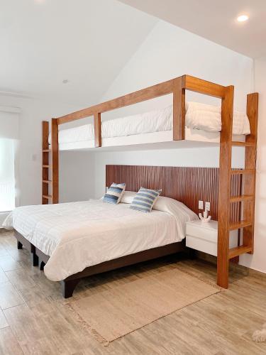 a bedroom with a bunk bed with white sheets and blue pillows at Casa Z Paracas in Paracas