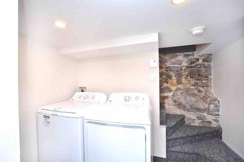 Una lavadora y secadora blancas en una habitación con pared de piedra. en BEAU 4 CHAMBRES AU COEUR DU PLATEAU MONT-ROYAL, en Montreal