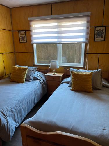 a bedroom with two beds and a window with a blind at Acogedora casa céntrica en Panguipulli in Panguipulli