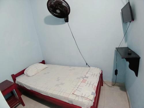 a small bedroom with a bed with a fan on the wall at Establecimiento luz y fer in San Vicente del CaguÃ¡n