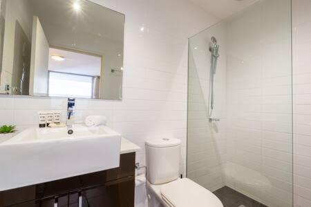 y baño con aseo, lavabo y espejo. en Sleek Inner-City Getaway in Prime Location en Sídney