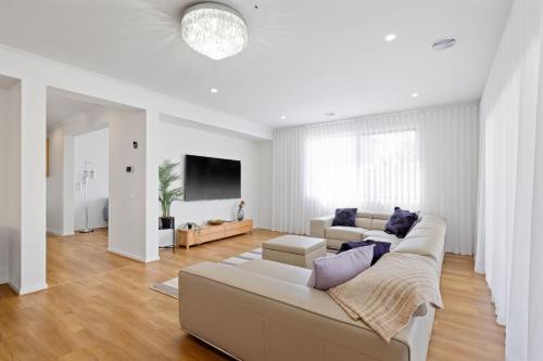 a white living room with a couch and a tv at Paterson Retreat in San Remo