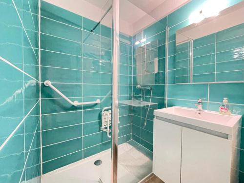 La salle de bains bleue est pourvue d'un lavabo et d'une douche. dans l'établissement Charmant T2 avec garage proche plage à Sète, animaux acceptés - FR-1-338-437, à Sète