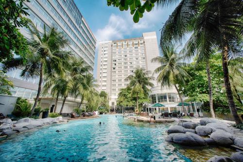a swimming pool in front of a building with palm trees at Wyndham Casablanca Jakarta in Jakarta