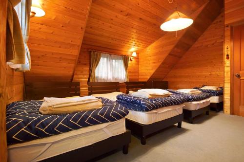 a room with four beds in a wooden cabin at Rental Log Urube Village in Tsumagoi