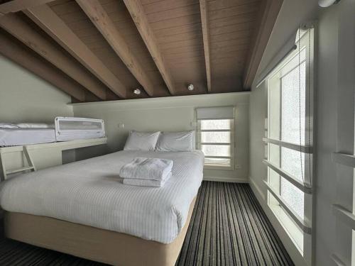 1 dormitorio con 1 cama con sábanas blancas y ventana en White Crystal 210 Ski In, Ski Out, en Monte Hotham