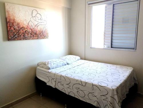 1 cama pequeña en un dormitorio con una pintura en la pared en Apto Centro Wifi Shopping Garage, en Taubaté