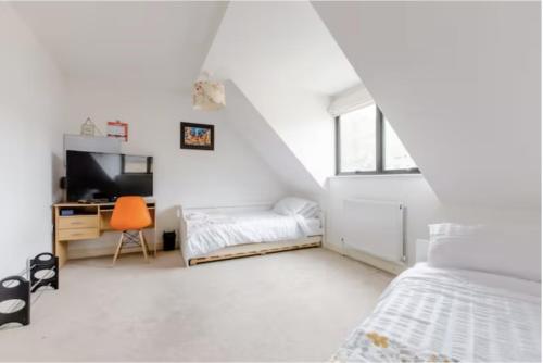 ein weißes Schlafzimmer mit einem Bett und einem Schreibtisch mit einem TV in der Unterkunft Chic DuoRooms with Modern Comfort for Families in Kent