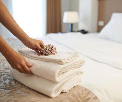 a person is putting towels on a bed at D'eluxe Hotel Talara- ubicado a 5 minutos del aeropuerto y a 8 minutos del centro civico in Talara