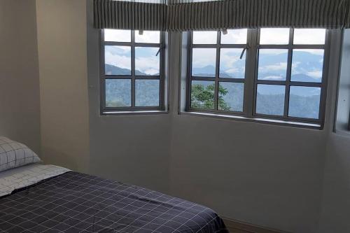 ein Schlafzimmer mit drei Fenstern und einem Bett darin in der Unterkunft Silverpar B5-5-1 Mountain View(walk up 2 floor up) in Bukit Fraser