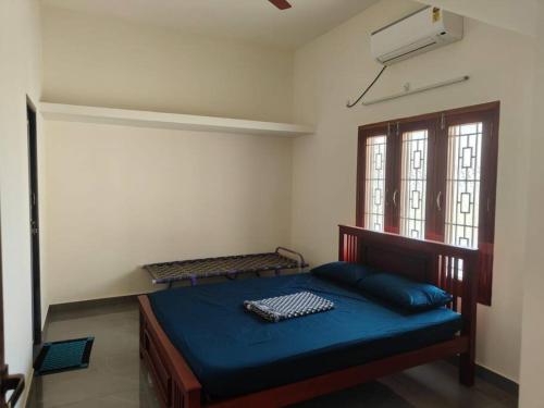 1 dormitorio con cama con sábanas azules y ventana en Wind Chimes, en Tiruvannāmalai