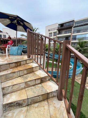 阿基拉斯的住宿－Beach Living - Apt com 2 Quartos - Pé na Areia，坐在游泳池旁楼梯上椅子上的男人