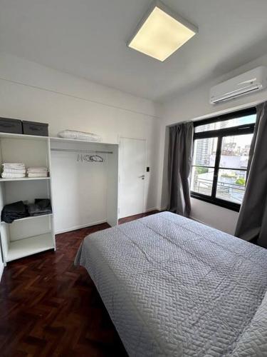 a white bedroom with a bed and a window at Departamento con vista al Abasto in Buenos Aires