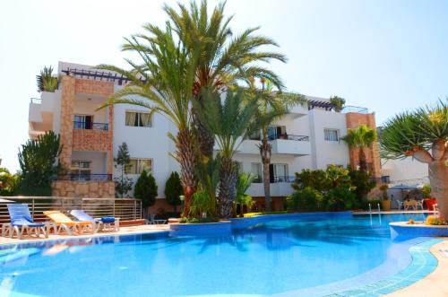 une grande piscine bordée de palmiers et un bâtiment dans l'établissement Golden Beach Appart'hotel, à Agadir