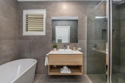 La salle de bains est pourvue d'une baignoire, d'un lavabo et d'une douche. dans l'établissement Charming 3BR Home in Bendigo, à Kennington