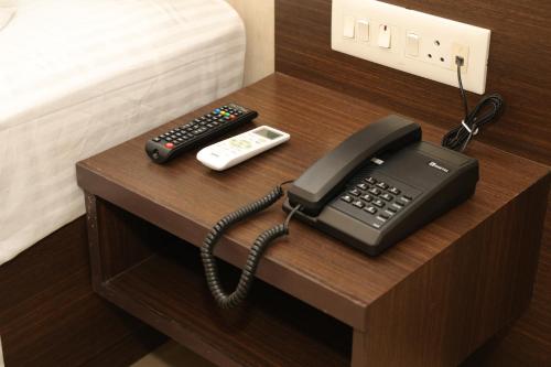 a desk with a telephone and a remote control at HOTEL SR in Palani
