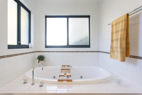 uma casa de banho branca com uma banheira e janelas em Stella Retreat - Townhouse with pool em East Fremantle