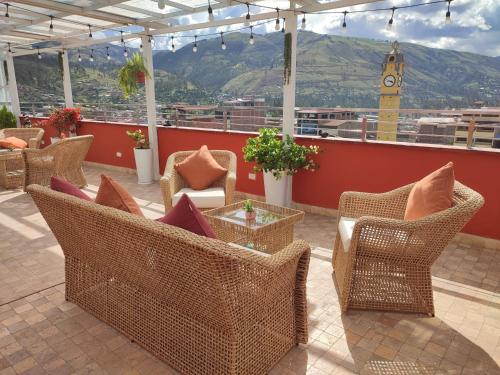 eine Terrasse mit Korbstühlen, einem Tisch und einem Uhrturm in der Unterkunft Chanka Suites in Talavera