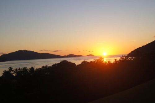 a sunset over the water with mountains in the background at Poinciana 106 in Hamilton Island