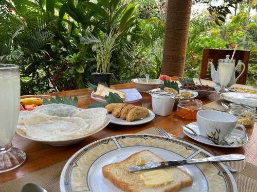 a wooden table topped with plates of bread and pastries at Green Mountain Villa in Ella