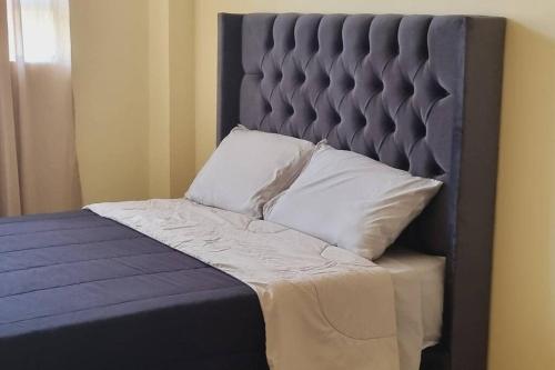 a bed with a blue headboard and two pillows at onechako101 in Víctor Larco Herrera