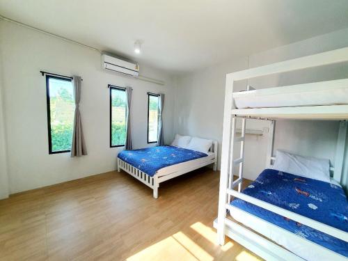 a bedroom with two bunk beds and two windows at Chalicha pool villa phatthalung in Khuan Khanun