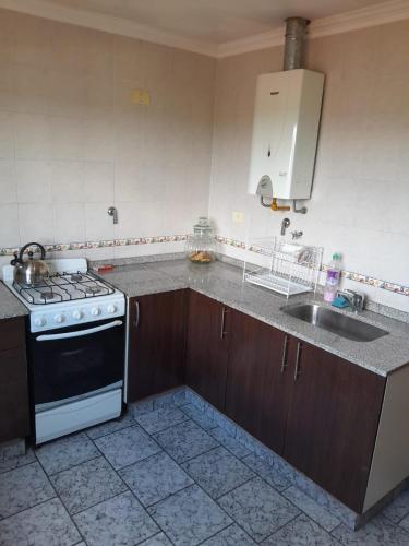 a kitchen with a stove and a sink at Departamento La Plaza in La Falda