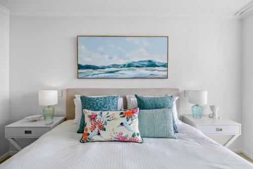 a bedroom with a bed with pillows and a painting on the wall at Beachside Stunning 3-Bed with Ocean View & Pool in Caloundra