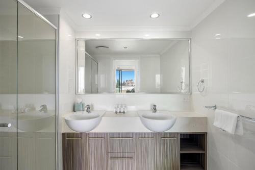 a bathroom with two sinks and a large mirror at Beachside Stunning 3-Bed with Ocean View & Pool in Caloundra
