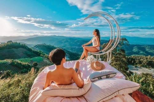 a boy and a girl sitting in a chair on top of a mountain at ไร่ดอยช้าง ม่อนเเจ่ม in Mon Jam