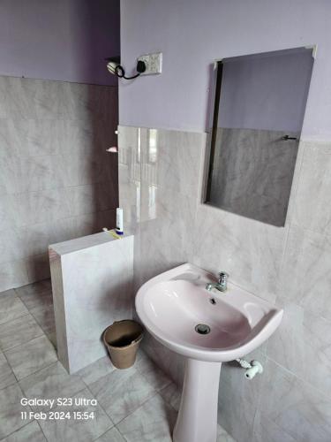 Baño blanco con lavabo y espejo en Kevin's Place, en Seeduwa