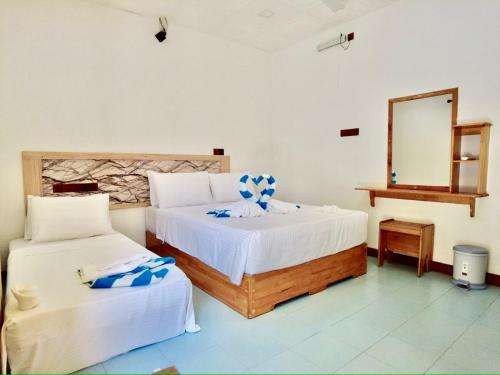 1 Schlafzimmer mit 2 Betten und einem Spiegel in der Unterkunft ONE SEASON THODDOO in Thoddoo-Atoll
