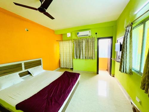 een slaapkamer met oranje en groene muren en een bed bij Hotel Falcon House ! Puri in Puri