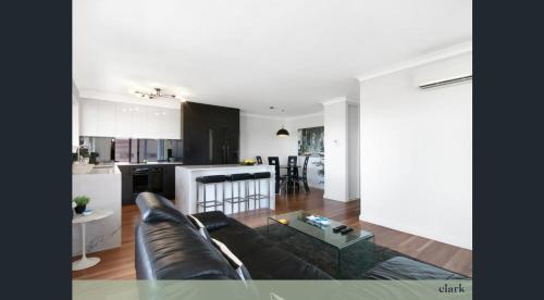 sala de estar con sofá negro y cocina en Best Value With City View Sleeps 7 en Brisbane