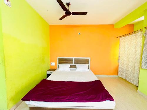 Cama en habitación con paredes de color amarillo y naranja en Hotel Falcon House ! Puri, en Puri