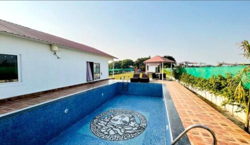 a villa with a swimming pool in front of a house at Banke bihari farm in Noida