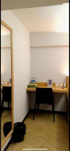 Cette chambre comprend un bureau avec une chaise et un miroir. dans l'établissement Pringgondani Guesthouse Sambiroto, à Jatingaleh