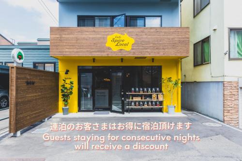 a store with a yellow sign on the front of a building at Ten to Ten Hostel in Sapporo