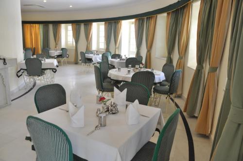 a dining room with tables and chairs and windows at Garden Hotel - Heritage by HRH Group of Hotels in Udaipur