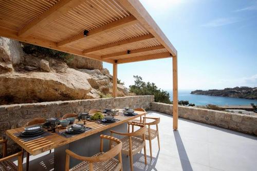 a wooden table and chairs on a patio with the ocean at Villa Mirage - Super Paradise beach in Mikonos