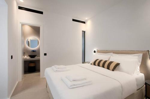 a white bedroom with a large bed and a bathroom at Villa Mirage - Super Paradise beach in Mikonos