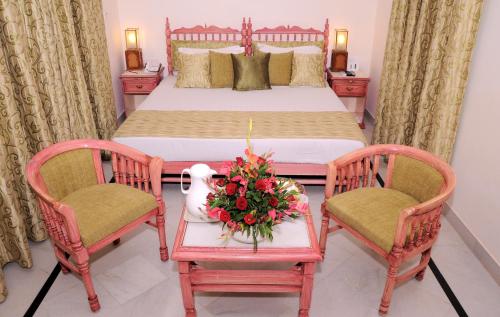 a bedroom with a bed with two chairs and a table with flowers at Garden Hotel - Heritage by HRH Group of Hotels in Udaipur