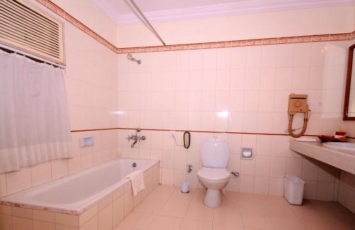 a bathroom with a tub and a toilet and a sink at Garden Hotel - Heritage by HRH Group of Hotels in Udaipur