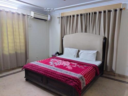 Hotel Sky Inn Clifton في كراتشي: غرفة نوم مع سرير مع بطانية حمراء عليه