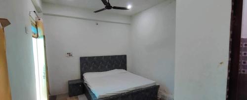 Cette chambre comprend un petit lit et un ventilateur de plafond. dans l'établissement OYO Gopal Hotel And Family Restaurant, à Gwalior