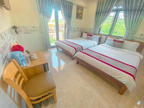 een slaapkamer met 2 bedden, een tafel en een bureau bij KHÁCH SẠN HƯNG THỊNH - Lý Sơn in Ly Son
