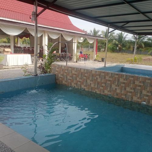 a pool of blue water in front of a building at HOMESTAY MY HUT in Merlimau